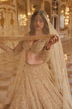 a woman in a gold lehenga and veil with sequins on it