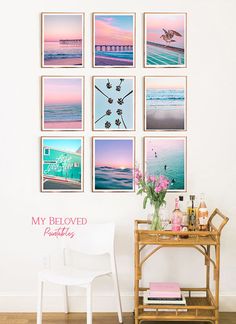 a white chair sitting next to a wooden table in front of a wall with pictures on it