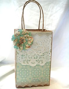 a small bag with a flower on the front and lace around it, sitting on a white background