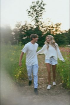 two people walking down a dirt road holding hands