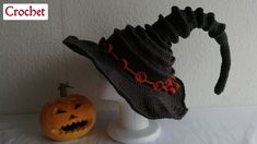 a crocheted hat is sitting next to a jack - o'- lantern