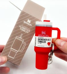 a red coffee mug shaped like a travel mug with a keychain attached to it