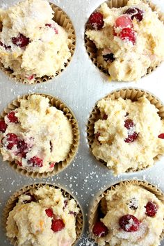 several muffins with cranberries and powdered sugar in them on a baking sheet