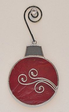 a red ornament hanging from a hook on a white wall with silver wire