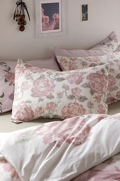 a bed with pink flowers on it in a bedroom next to a framed photograph and pictures