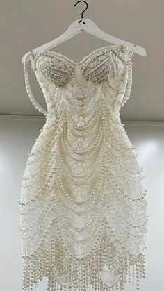 a white dress hanging on a hanger in a room with no one wearing it