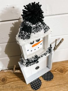 a snowman made out of an old window frame with black and white decorations on it