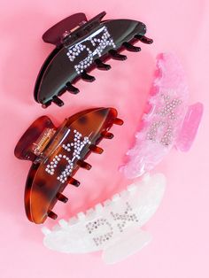 three hair combs with different designs and colors on pink background next to each other