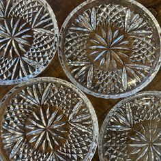 four clear glass plates sitting on top of a wooden table