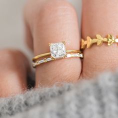 a woman's hand with two gold rings on it and a diamond in the middle