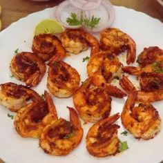 some shrimp on a white plate with lemon wedges and cilantro garnish