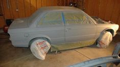 a white car is being worked on in a garage with plastic wrapped around the hood