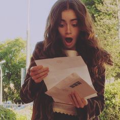 a woman is holding papers and looking surprised