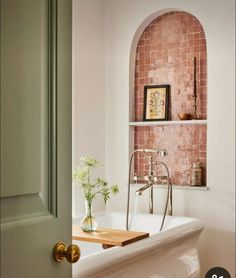 a bath tub sitting under a window next to a shelf with vases on it