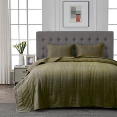 a bed with a green bedspread and pillows