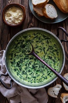 a pot filled with green liquid next to bread