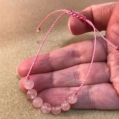 These soft pink rose quartz bracelets are fashionable and healing! Rugged and durable for 24/7 wear, but, still dainty, natural and feminine for her, this rose quartz bracelet is perfect for the whole family, gift giving. party favors, wedding parties and even for a gender reveal! This genuine gemstone bracelet features seven round 6mm rose quartz beads in the center of a comfy knotted bracelet. This trendy string bracelet is strung on durable high quality heavy braided nylon cord with a sliding Minimalist Pink Round Bracelet, Casual Rose Quartz Jewelry Gift, Casual Pink Sliding Knot Jewelry, Adjustable Rose Quartz Bracelets - Spiritual Style, Pink Adjustable Beaded Bracelets For Healing, Adjustable Pink Gemstone Beaded Bracelets, Pink Adjustable Spiritual Braided Bracelet, Casual Pink Beaded Bracelets With Adjustable Cord, Casual Rose Quartz Bracelets For Gifts