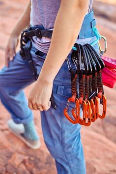 a woman holding several pairs of scissors in her hand and wearing an orange safety belt