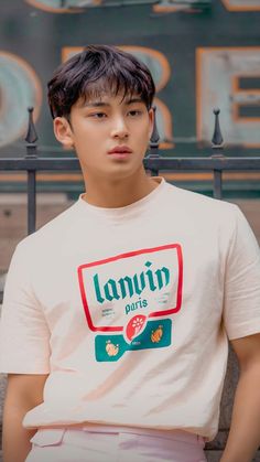 a young man sitting on a bench in front of a sign that reads lanjui paris