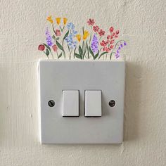 a white light switch with flowers painted on the wall next to it and an electrical outlet