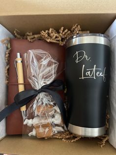 an open box containing a coffee cup, chocolates and a pen