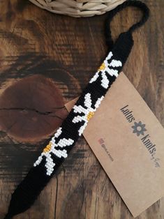 a black and white crochet bracelet with flowers on it sitting next to a basket