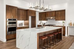 a kitchen with wooden cabinets and white marble counter tops, an island with four stools