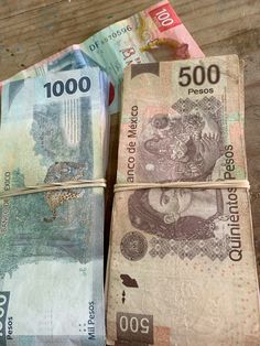 three bundles of mexican currency sitting next to each other on top of a wooden table