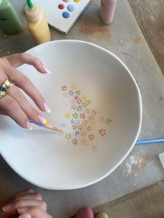 a woman's hand with painted nails is in a white bowl on the table