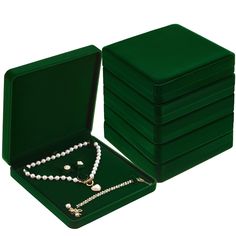 a set of six green velvet jewelry boxes with pearl necklaces and matching bracelets