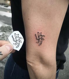 a person with a tattoo on their arm holding up a sticker that says cat