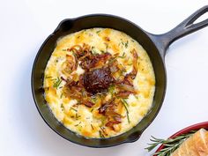 an omelet with bacon and cheese in a skillet on a white surface