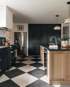 a black and white checkered floor in a kitchen with an island, stove, sink, refrigerator and dishwasher