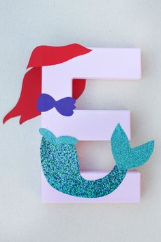 the letter e is made out of paper and has a mermaid tail on it's head