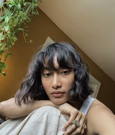 a woman laying on top of a bed next to a plant