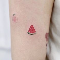 a watermelon tattoo on the back of a woman's arm, with an apple in the background