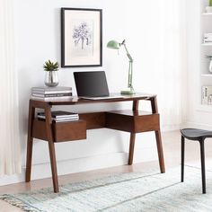 a desk with a laptop on it in front of a white wall and a chair