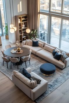 a living room filled with lots of furniture next to large windows on top of a wooden floor