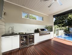 an outdoor kitchen with wood flooring and sliding glass doors that open up to the pool