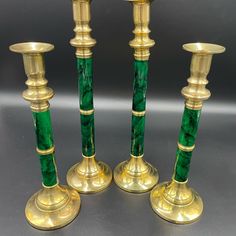 three green candlesticks sitting next to each other on top of a black table