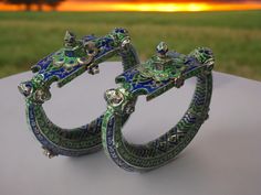 a couple Fine  Champleve Enamel  Anklets (Jhanhjar) Jhanjar anklets are large hollow rings which rattle when the wearer walks.The enamels on these jhanjhar anklets are champleve Punjab, Pakistan 19th century diameters at widest point: 13 cm, combined weight: 441g This spectacular  anklets is from the Punjab area of what is now Pakistan. Possibly such anklets were worn at weddings. They are of hollow sheet silver and have been chased and repoussed and then decorated with green and dark blue ename Bohemian Bracelets For Diwali Ceremonial, Bohemian Cutdana Bracelets As Gift, Handmade Bangle For Ceremonial Festive Occasions, Handmade Ceremonial Bangle For Diwali, Bohemian Adjustable Cutdana Bracelet, Adjustable Bohemian Cutdana Bracelet, Bohemian Meenakari Bracelets For Diwali, Ceremonial Green Bracelets With Tilla Detail, Traditional Multicolor Ceremonial Bracelets