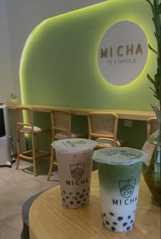 two iced drinks sitting on top of a table in front of a neon green wall