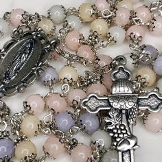 "Handmade traditional Catholic 5 decade rosary using morganite dyed jade smooth stone round beads. Antique silver flower bead caps on every bead. Silver Our Lady of Guadalupe center with Holy Communion cross featuring Holy Eucharist, Chalice and JHS Christogram. All beads are 6mm. Designed to be used and/or displayed. Measures about 22\" long. This rosary would make a beautiful gift for any girl receiving their First Communion. Comes in a beautiful black velvet pouch. I ship same or next business day. All of my rosaries are one of a kind and are my own personal creation. Photos are a part of the description-you will receive the exact rosary pictured. Please don't hesitate to reach out if you have any questions! God Bless!" Silver Gemstone Beads And Cabochons, Silver Polished Beads For Spiritual Use, Polished Round Beads Rosary For Jewelry Making, Silver Rosary With 8mm Beads For Healing, Spiritual Silver Polished Beads, Silver Gemstone Round Beads, Pink Rosary With Round Beads For First Communion, Pink Beaded Rosary With Round Beads, Silver Rosary With Natural Stones And Round Beads