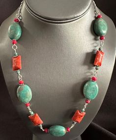 A stunning combination of blue turquoise and vibrant red coral, embellished with intricate Bali beads, adorns a sleek silver chain. This versatile necklace can be adjusted from 16 to 21 inches in length. Adjustable Red Coral Gemstone Beads Necklace, Red Multi-strand Coral Beaded Necklaces, Coral Accents, Unique Hand-strung Red Coral Necklaces, Adjustable Hand-strung Red Coral Necklace, Multi-strand Red Coral Necklace With Polished Beads, Red Coral, Turquoise Blue, Vibrant Red