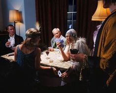 a group of people sitting around a table drinking wine and playing cards games with each other