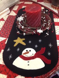 a red candle is sitting on top of a snowman placemat that has been decorated