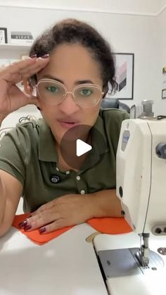 a woman wearing glasses is looking at the camera while she sews on a sewing machine