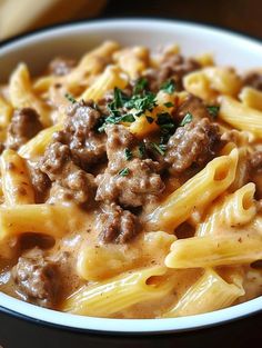 a close up of a bowl of food with pasta and meat in it on a table