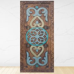 a wooden panel with an intricate design on it's side, in front of a white wall