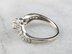 This diamond engagement ring has a simplicity and grace which is beautiful and quite unique. A round diamond is prong-set in a modern bypass mounting, sparkling diamonds add a little bit of extra glitter to the modernist setting! Metal: 10K White Gold Gem: Diamond .40 Carats, H in Color, SI3 in Clarity Gem Measurements: 4.6 mm, Round Accents: 32 Diamonds totaling .80 Carats, G in Color, SI in Clarity Ring Size: 6.25 Marks: "10K" Stamped on the inside band Yellow Gold Sapphire Ring, Jewelry Stacking, Bypass Ring, Engagement Ring White Gold, Ring White Gold, Cameo Ring, White Gold Diamond Rings, Gold Diamond Rings, Sparkle Diamonds